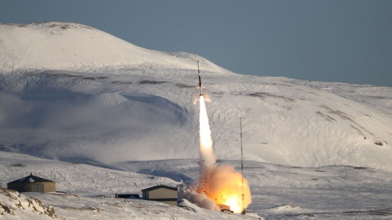 A rocket takes off from a field of ice and snow.